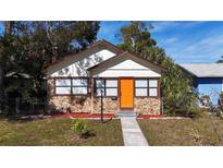 Charming single Gathering home with a stone facade, orange door, and manicured front lawn at 4219 4Th S Ave, St Petersburg, FL 33711