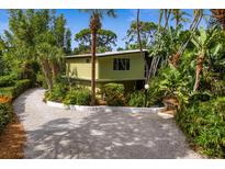 Mid-century modern home nestled in lush tropical landscaping, featuring a unique curved driveway at 711 Pinellas Point S Dr, St Petersburg, FL 33705