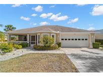 Single-story home with a two-car garage and landscaped front yard at 1311 Caloosa Lake Ct, Sun City Center, FL 33573