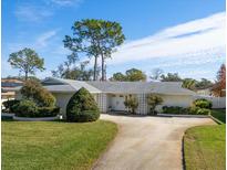 Ranch-style home with a spacious yard and attached two-car garage at 2389 Sarazen Dr, Dunedin, FL 34698