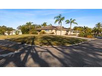 Charming single story home featuring a circular driveway, large front lawn, and beautiful landscaping with palm trees at 4001 Harbor Hills Dr, Largo, FL 33770