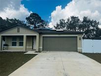 Tan house with gray garage door, solar panels, and a white fence at 8303 Begonia St, Spring Hill, FL 34608