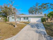 Ranch-style home with a white garage door and a spacious driveway at 310 Shirley Dr, Largo, FL 33770