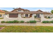 Charming stucco home with a tile roof, arched entryway, gated courtyard, and well-maintained landscaping at 3903 Sand Dollar Pl, Tampa, FL 33634