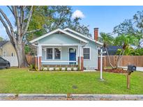 Charming bungalow featuring a cozy porch, light blue exterior, brick accents, and a well-manicured front yard at 705 W Kentucky Ave, Tampa, FL 33603