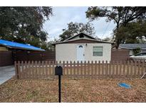 Charming single-story home featuring a decorative front door, textured walls, a fenced yard, and a mailbox at 8014 N Alaska St, Tampa, FL 33604