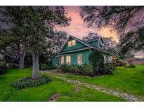 Charming green two-story home with lush landscaping and stone pathway during a colorful sunset at 10350 54Th N Ave, St Petersburg, FL 33708
