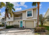 Two-story condo with teal door, attached garage, and palm trees at 223 Sun Vista S Ct, Treasure Island, FL 33706