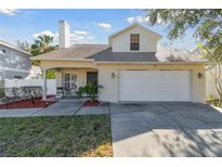 Two-story house with a white exterior, attached garage, and landscaped front yard at 3118 W Hartnett Ave, Tampa, FL 33611
