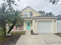 Charming yellow house with rocking chairs on the porch and a two-car garage at 5607 Tanagergrove Way, Lithia, FL 33547