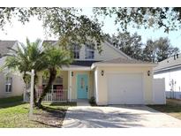 Charming two-story home featuring a light yellow exterior, single car garage, and a cozy front porch with rocking chairs at 5607 Tanagergrove Way, Lithia, FL 33547