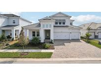 Two-story home with white exterior, paver driveway and landscaping at 10406 Longmeadow Ave, Parrish, FL 34219