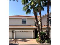 Tan two-story townhome with double garage and palm trees at 1314 Riserva Ln, Palm Harbor, FL 34683