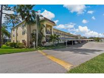 Well-maintained condo complex with assigned covered parking and mature landscaping on a sunny day at 1450 Heather Ridge Blvd # 305, Dunedin, FL 34698