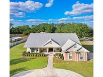 Expansive property featuring a well-maintained lawn, circular driveway, and metal roof at 1702 W Knights Griffin Rd, Plant City, FL 33565