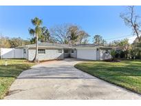 Gray brick ranch house with a two-car garage and landscaped yard at 18615 Yocam Ave, Lutz, FL 33549