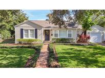 Charming home features a manicured lawn and a brick walkway to the front door at 212 S Himes Ave, Tampa, FL 33609