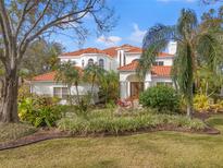 Stunning white home with a terracotta roof, lush landscaping and mature trees at 7401 Watersilk Dr, Pinellas Park, FL 33782