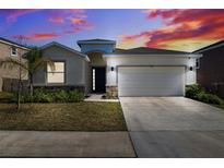 Charming home featuring a two-car garage and a well-manicured front lawn, set against a vibrant sky at 9804 Rowing Dale Bnd, Wesley Chapel, FL 33545