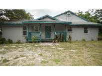 Gray house with teal accents and porch at 12217 Peaceful Ave, Weeki Wachee, FL 34614