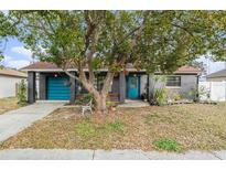 Gray house with teal door, mature tree, and landscaping at 1232 Calamondin Dr, Holiday, FL 34691