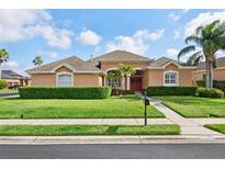 Charming single-story home with manicured lawn, mature landscaping, and a welcoming red front door at 1642 Daylily Dr, Trinity, FL 34655