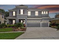 Two-story house with gray siding, three car garage, and landscaped front yard at 19322 Autumn Chase Ct, Land O Lakes, FL 34638