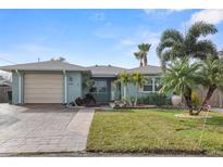 Charming single-story home featuring a well-manicured lawn, palm trees, and a brick-paved driveway leading to an attached garage at 6702 Harbor Dr, Hudson, FL 34667