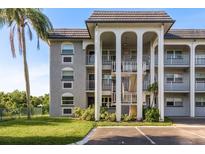 Three-story condo with a gray brick facade, white columns, and landscaped grounds at 1303 S Hercules Ave # 1, Clearwater, FL 33764