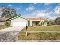 Charming single-story home featuring a well-manicured lawn, a two car garage, and a red front door at 17512 Brandywine Dr, Lutz, FL 33549