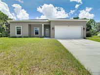 New construction home with gray exterior, two-car garage, and manicured lawn at 493 Omen St, Punta Gorda, FL 33982