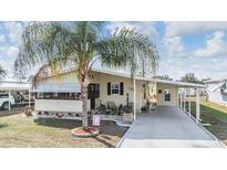 Charming single-story home featuring a covered carport, a cozy front porch, and a well-maintained lawn at 5539 Regal Way, Zephyrhills, FL 33541