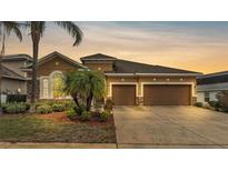 Two-story house with three-car garage, stone accents, and landscaping at 1030 Tracey Ann Loop, Seffner, FL 33584