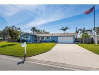 Charming single-story home with a well-manicured lawn, long driveway, and an American flag waving proudly at 1745 Emerald Dr, Clearwater, FL 33756