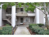 Inviting condo exterior featuring well-maintained landscaping and neutral colors. Walkway leads to a covered porch at 5265 E Bay Dr # 323, Clearwater, FL 33764