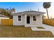 Newly constructed home with gray exterior, a covered porch, and a fenced yard at 701 E Wood St, Tampa, FL 33604