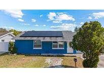 Charming single-story home showcasing a blue painted exterior, solar panels, and well-maintained landscaping at 8903 Bay Bridge Ct, Tampa, FL 33634