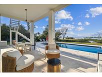 Inviting covered patio with stylish furniture and a refreshing pool overlooking the scenic waterfront at 1640 Sea Breeze Dr, Tarpon Springs, FL 34689