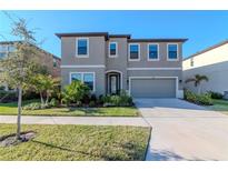 Two-story home showcasing well-maintained landscaping, complemented by a neatly manicured lawn and a driveway leading to an attached garage at 12625 Horseshoe Bend Dr, Lithia, FL 33547