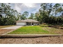 Charming single-story home featuring a well-manicured lawn and attached two-car garage, set amongst mature trees at 26890 Hiawatha Blvd, Brooksville, FL 34601