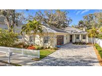 Charming, light-yellow single Gathering home with a brick driveway and white picket fence at 415 5Th N St, Safety Harbor, FL 34695