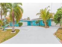 Charming waterfront home with a light blue exterior, palm trees, and a large driveway at 4643 Bay Crest Dr, Tampa, FL 33615