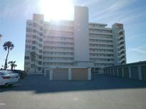 Multi-story condominium building with parking lot, garages, and palm trees on a sunny day at 7000 Beach Plz # 805, St Pete Beach, FL 33706