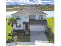 Two-story house with gray roof and stone accents, showcasing a three-car garage and well-manicured lawn at 2302 Village Amble Loop, Lutz, FL 33558