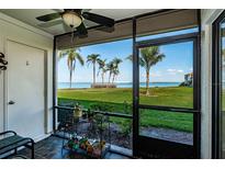 Screened patio features views of manicured green lawn with palms and serene waters at 6211 Sun Blvd # 115, St Petersburg, FL 33715