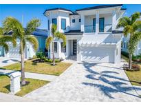 Elegant two-story home with a white exterior, large driveway, palm trees and well-manicured lawn at 6536 Simone Shores Cir, Apollo Beach, FL 33572