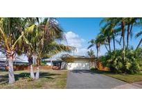 Charming single-story home with a two-car garage, driveway, and palm trees in the front yard at 2666 Red Oak Ct, Clearwater, FL 33761