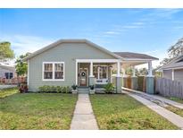 Charming single-story home with a cozy front porch, manicured lawn, and a convenient carport at 1211 E Giddens Ave, Tampa, FL 33603