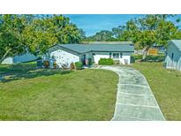 Charming single-story home featuring a long driveway and a well-manicured lawn with mature trees at 1436 Rose St, Clearwater, FL 33756