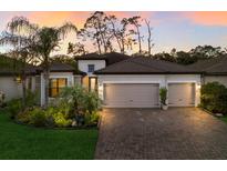 Beautiful single-Gathering home featuring a three-car garage, brick driveway, and lush tropical landscaping at 706 Acacia Ct, Bradenton, FL 34212